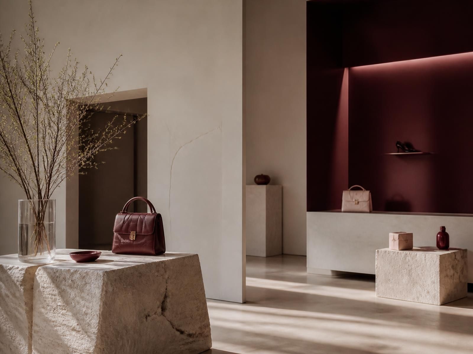 Minimal luxury boutique interior with stone plinths and burgundy alcove